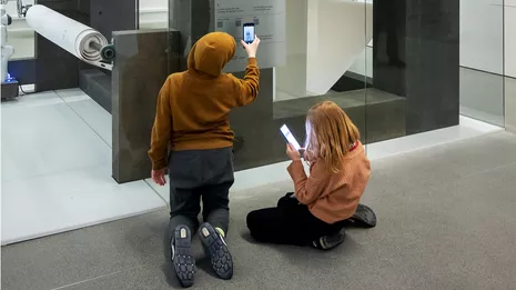 Kinder nutzen das Smartphone, um mit dem zeichnenden Roboter zu interagieren. Foto: Astrid Eckert / TUM